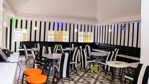 Un restaurant amb parets de tires negres i blanques, diverses taules i caires, i un terra amb disseny.