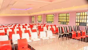 A conference room with rows of chairs, large windows, and a logo on the wall.