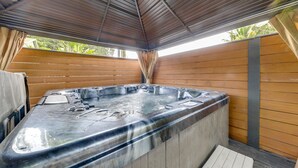 Un jacuzzi con cubierta de madera y techo metálico.