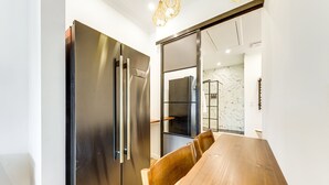 Una cocina moderna con un refrigerador de acero inoxidable, una mesa de comedor de madera y sillas.