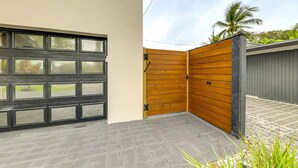 Un garaje moderno con una puerta negra grande y un portón de madera.