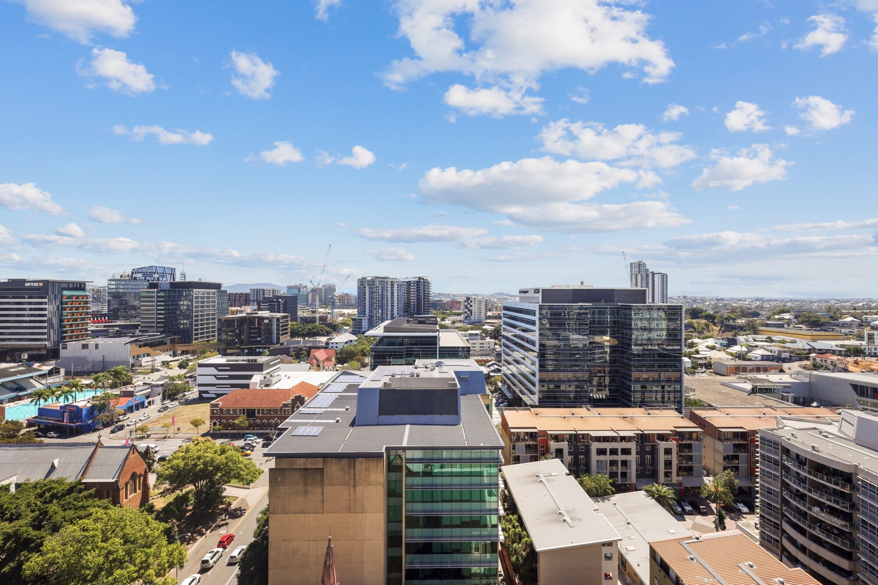 A cityscape with modern buildings, including a mix of high-rise and low-rise structures, under a clear sky.