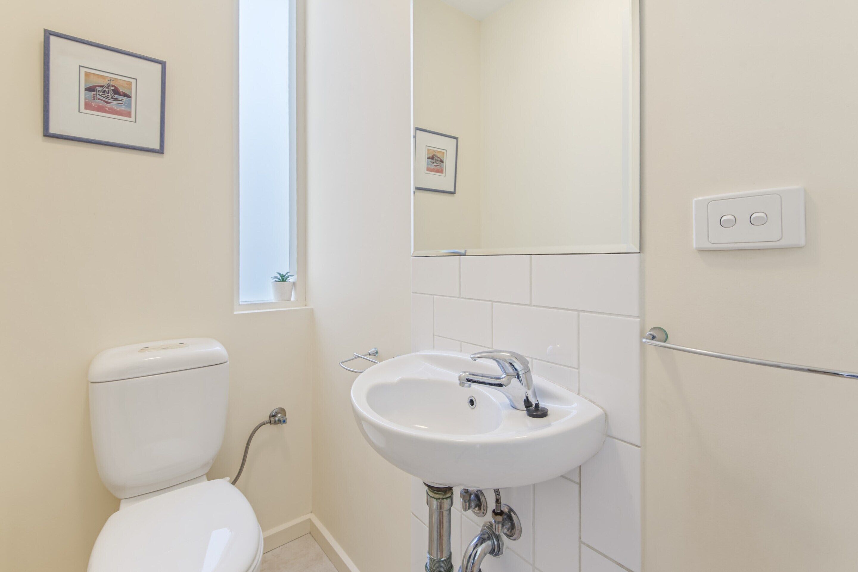 A bathroom with a toilet, sink, and a mirror.
