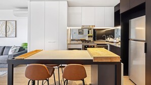 A modern kitchen with a central island, stainless steel appliances, and a dark cabinetry design. - Cosy 2-bed With Pool, Bbq Area and Secure Parking (Brisbane)