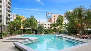 A swimming pool with steps leading into it, surrounded by lounge chairs and palm trees. - Cosy 2-bed With Pool, Bbq Area and Secure Parking (Brisbane)