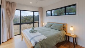 A bedroom with a large window, a bed, a bedside table with a lamp, and a ceiling fan. - Off-grid Farm Stay With Scenic Views (Tenterfield)