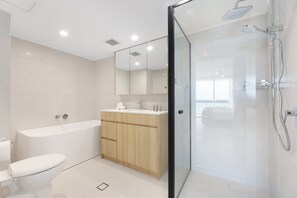 A modern bathroom with a bathtub, toilet, and shower area. - Beachfront Stylish Apartment With Ocean Views (Gold Coast)