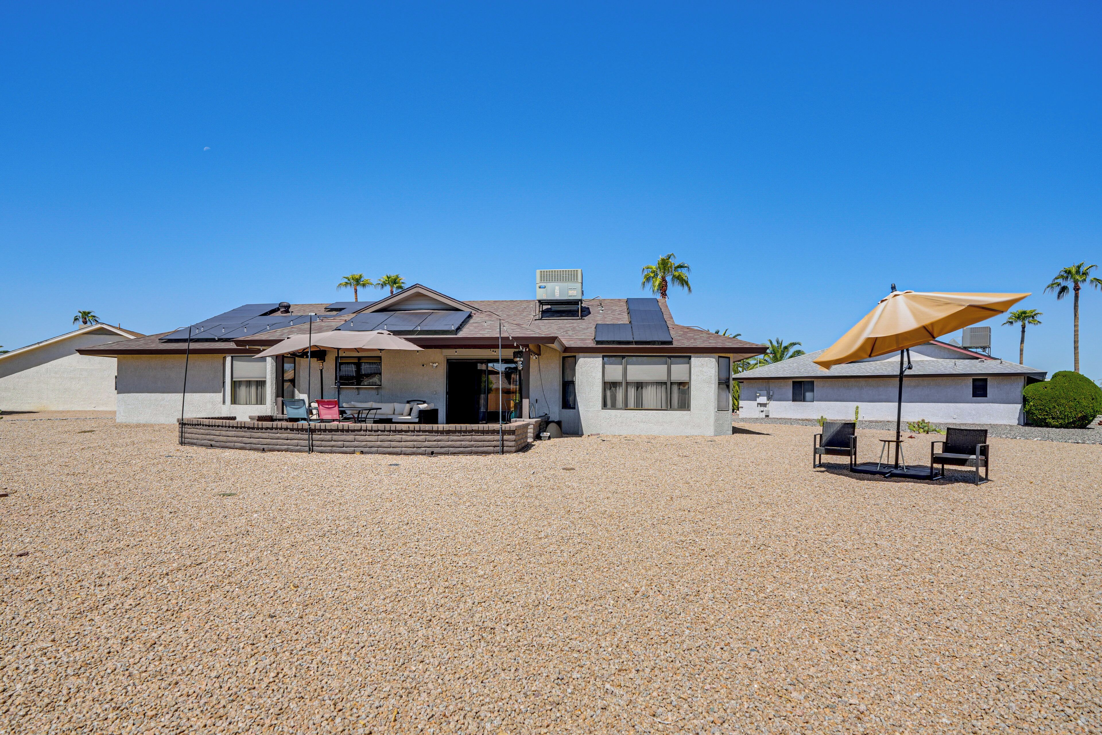 A house with solar panels, a covered patio, and a gravel driveway.