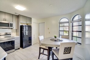 A modern kitchen with stainless steel appliances, a dining table with chairs, and large windows. - Lanai + Backyard! Sunny Retreat in Palm Bay (Palm Bay)