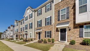 Une rangée de maisons de ville aux façades en pierre, dotées de petits porches et de petits jardins devant.
