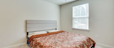 Un dormitorio con cama, ventana con persianas y una lámpara en el techo.