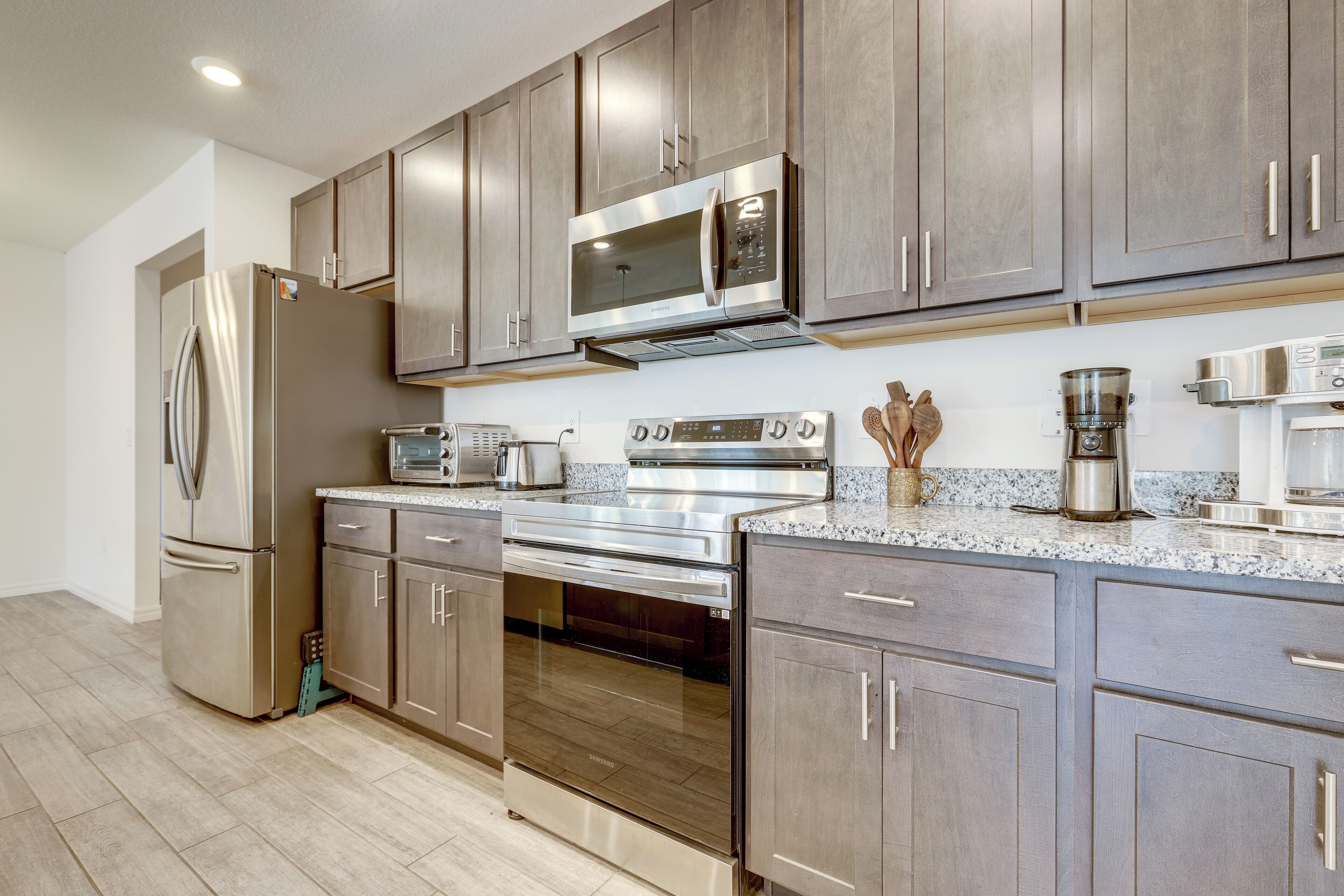 A modern kitchen with stainless steel appliances, wooden cabinets, and a granite countertop.