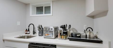 Cozinha moderna equipada com lava-louças embutida, torradeira, chaleira e diversos utensílios de cozinha.