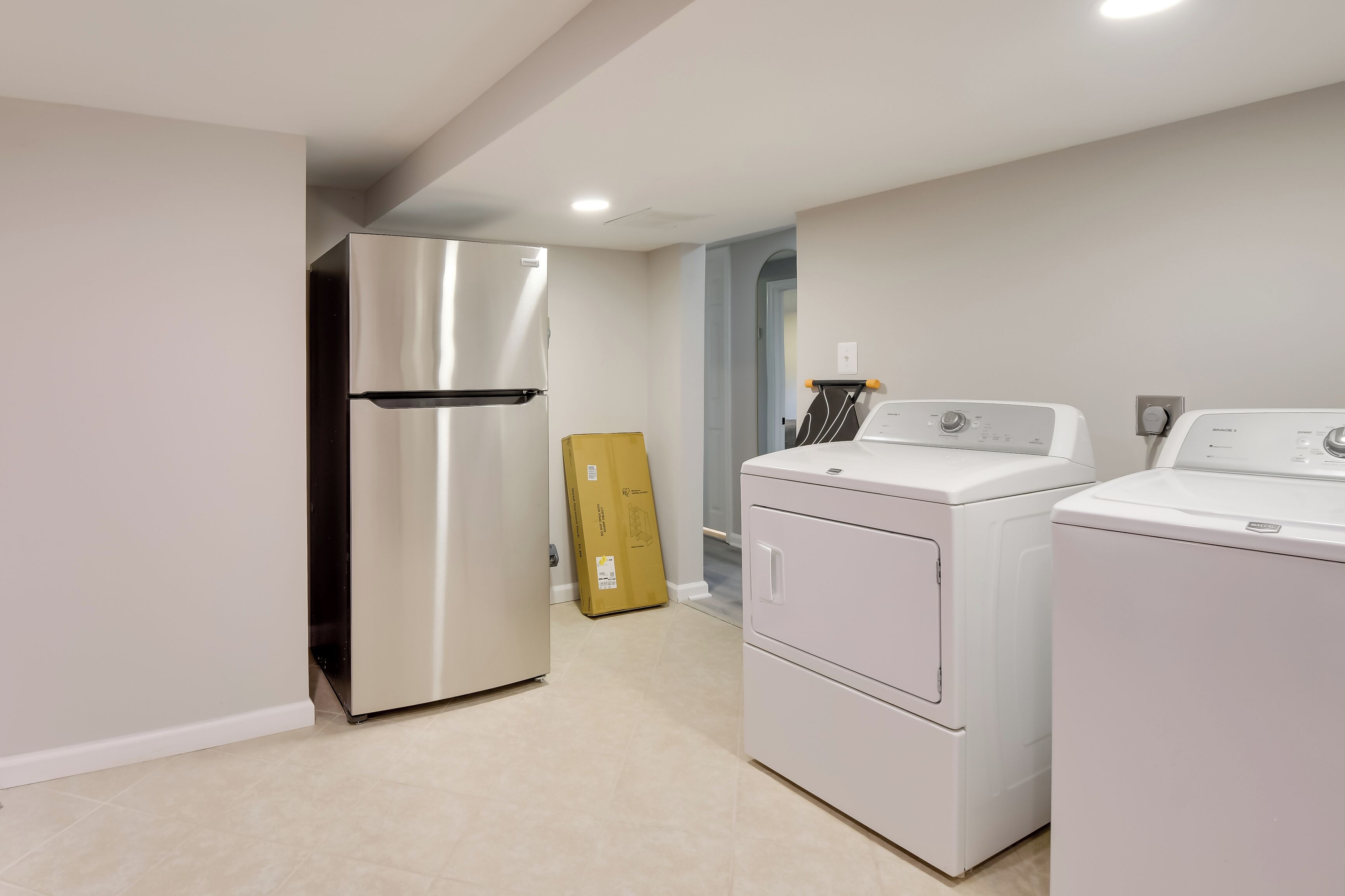 A compact kitchen with a stainless steel refrigerator, a washing machine, and a dryer.
