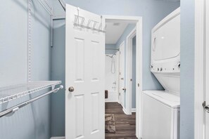 A laundry room with a white washing machine, a drying rack, and a towel rack.