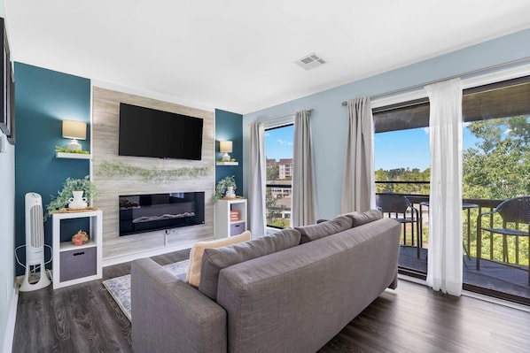 A modern living room with a flat-screen TV, grey sofa, and a fireplace.