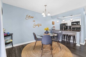 A dining area with a round table, chairs, and a wall with a decorative sign.