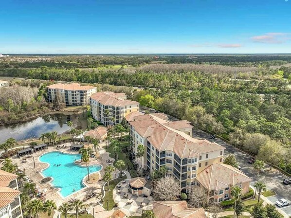 A resort with multiple buildings, a swimming pool, and surrounding greenery.