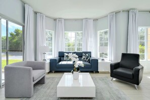 A modern living room with a grey sofa, a black armchair, and a white coffee table. - Serene Disney Getaway, Designer Style, MP61 (Orlando)