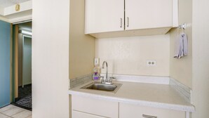 A kitchen with a stainless steel sink, white cabinets, and a tiled backsplash. - Walkable Urban Retreat! Condo in Honolulu (Honolulu)