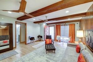 A spacious living room with a high ceiling, wooden beams, a leather armchair, a sofa, and a ceiling fan. - Convenient Condo 8 Mi to Dtwn Indianapolis! (Indianapolis)