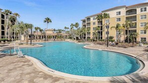 A swimming pool surrounded by palm trees and a multi-story building with balconies. - Sleek & Stylish Stay, Mins to Magic, MP68 (Orlando)