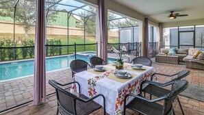 An outdoor patio with a pool, dining table, chairs, and a sofa. - Championsgate Resort Perks! Fun-filled Family Home (Davenport)