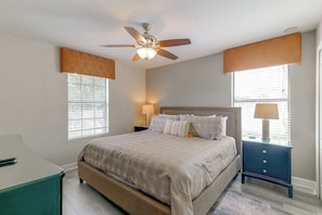 A bedroom with a bed, two bedside lamps, a ceiling fan, and a window with blinds. - Championsgate Resort Perks! Fun-filled Family Home (Davenport)