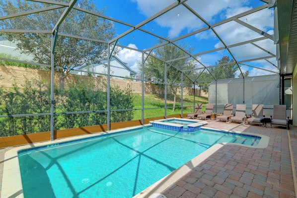 An indoor swimming pool with a clear view of the surrounding landscape, including trees and a house.