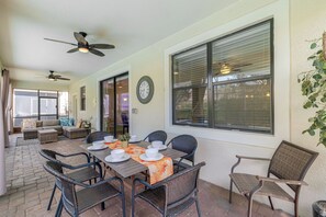 An outdoor patio with a table set for dining, surrounded by wicker chairs, and a ceiling fan above. - Championsgate Resort Perks! Fun-filled Family Home (Davenport)