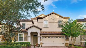 A two-story house with a garage, stone facade, and a well-maintained front yard. - Championsgate Resort Perks! Fun-filled Family Home (Davenport)