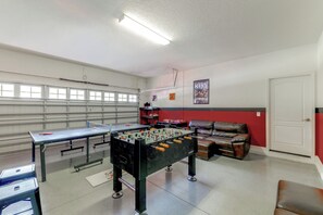 Una habitación con una mesa de futbolín, un sofá y una puerta.