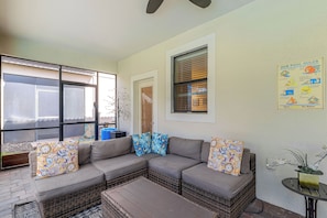 A sunlit patio area with a cushioned seating arrangement, a small table, and a decorative plant. - Championsgate Resort Perks! Fun-filled Family Home (Davenport)