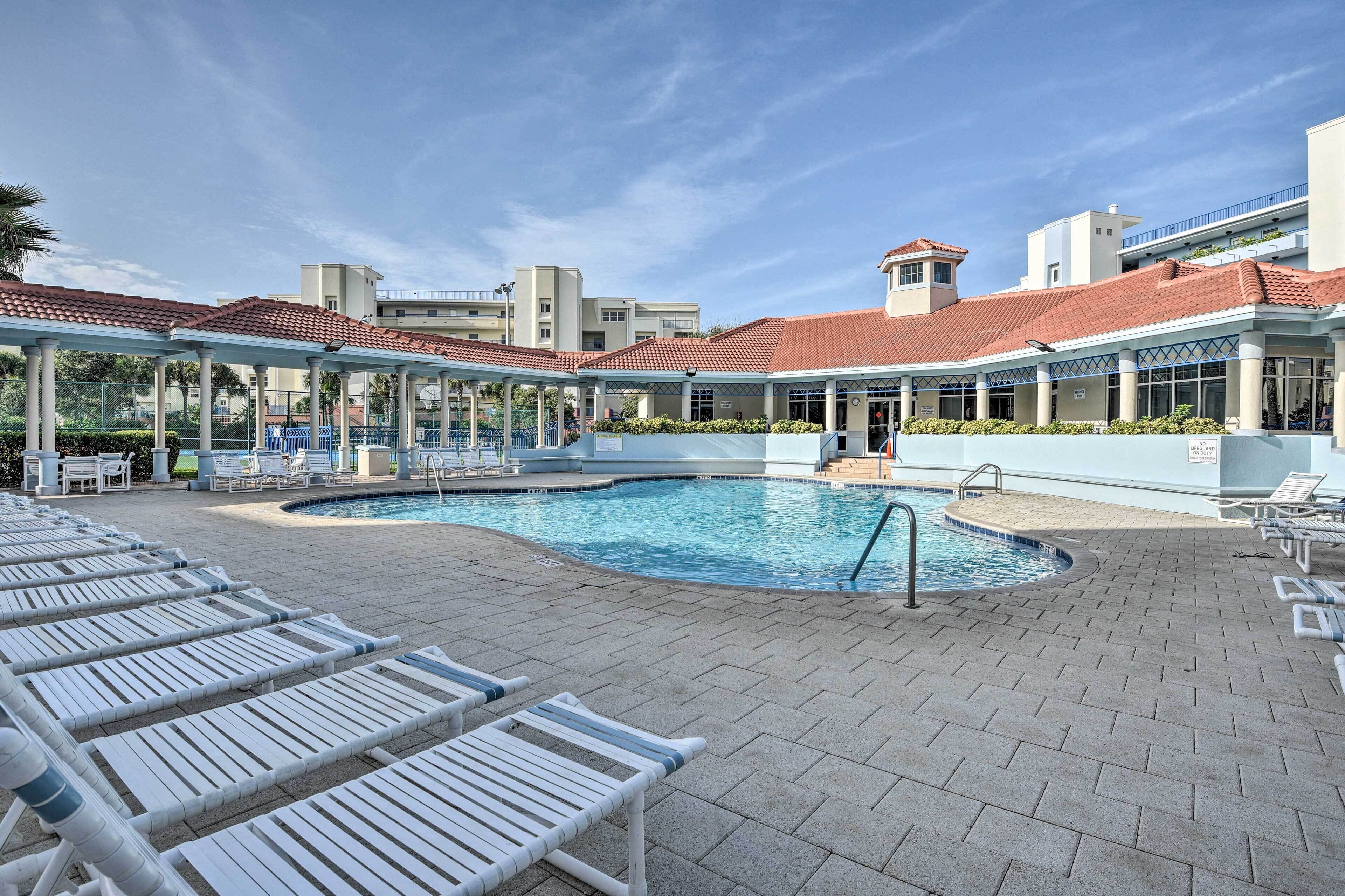 A pool area with lounge chairs and a covered seating area.