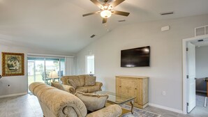 A living room with two beige sofas, a glass coffee table, a wooden cabinet, and a ceiling fan. - Fish, Golf & Beach-hop! Family Home in Cape Coral (Cape Coral)