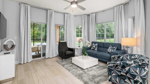 Un salon moderne avec un ventilateur de plafond, un canapé, une table basse et un téléviseur.