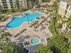 Resort com piscina grande, áreas de estar e vegetação ao redor.