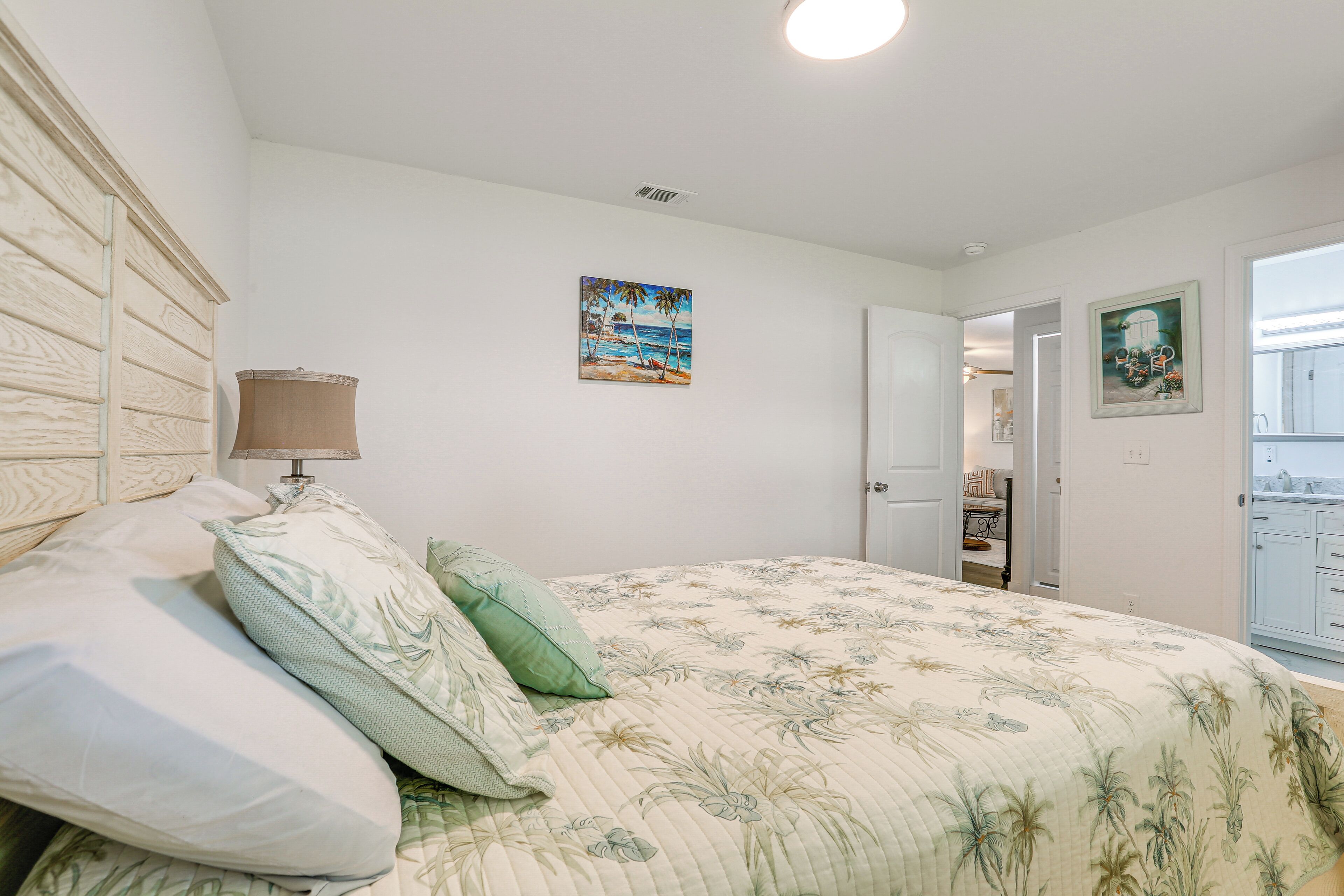 Un dormitorio con cama, almohadas, una lámpara y un cuadro en la pared.