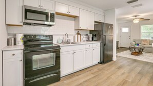 A modern kitchen with white cabinets, stainless steel appliances, and a wooden floor. - 2 Mi to River District! Fort Myers Retreat w/ Yard (Fort Myers)