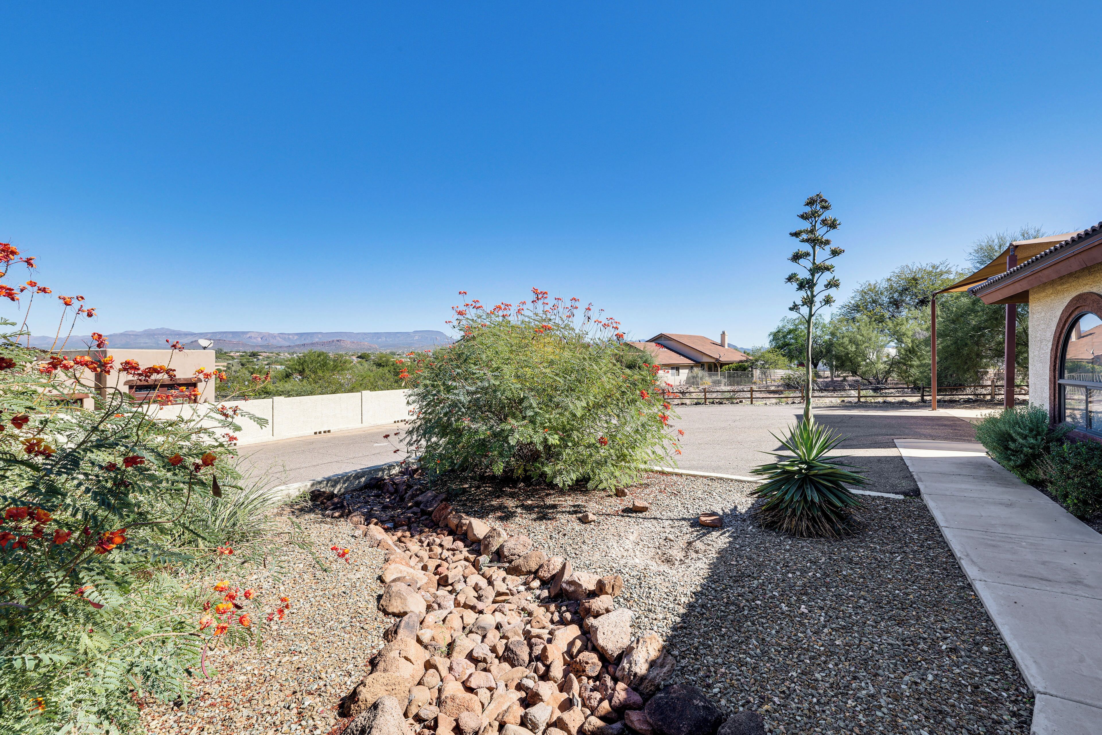 A landscaped garden with a pathway, a small building with a tiled roof, and a clear blue sky.