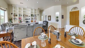 A dining area with a wooden table set for six, surrounded by grey sofas and wooden chairs. - Groups Welcome! Home w/ Pool + Patio in N Phoenix (Phoenix)