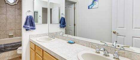 Un baño con dos lavamanos, un espejo grande, armarios de madera y un perchero para toallas.