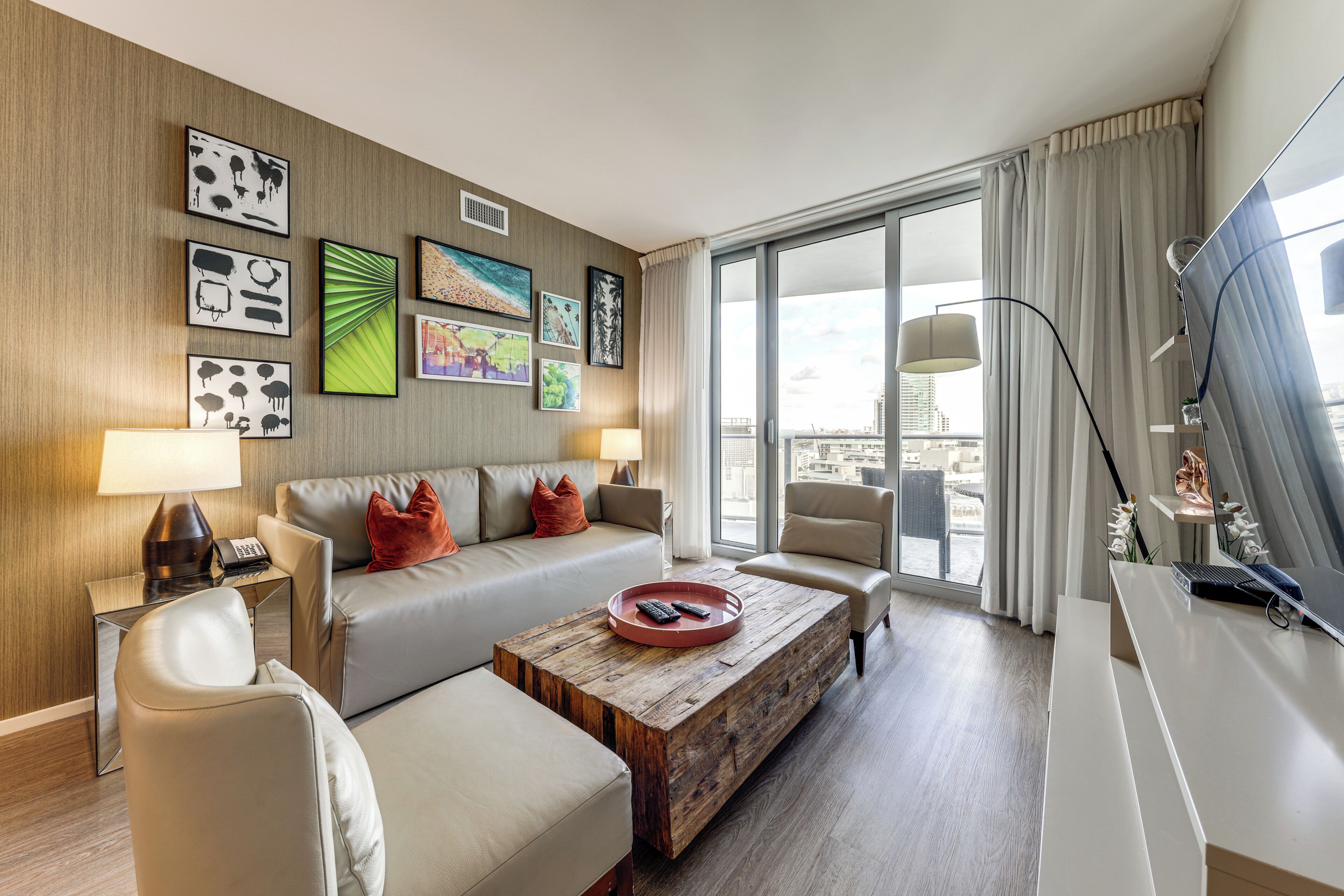 A modern hotel room with a sofa, armchairs, a coffee table, and artwork on the walls.