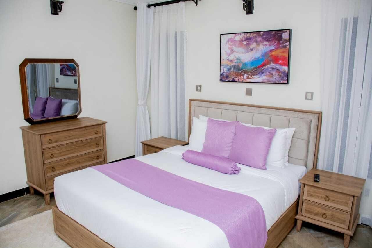 Un dormitorio con una cama grande, una mesita de noche, un aparador, un espejo y un cuadro en la pared.