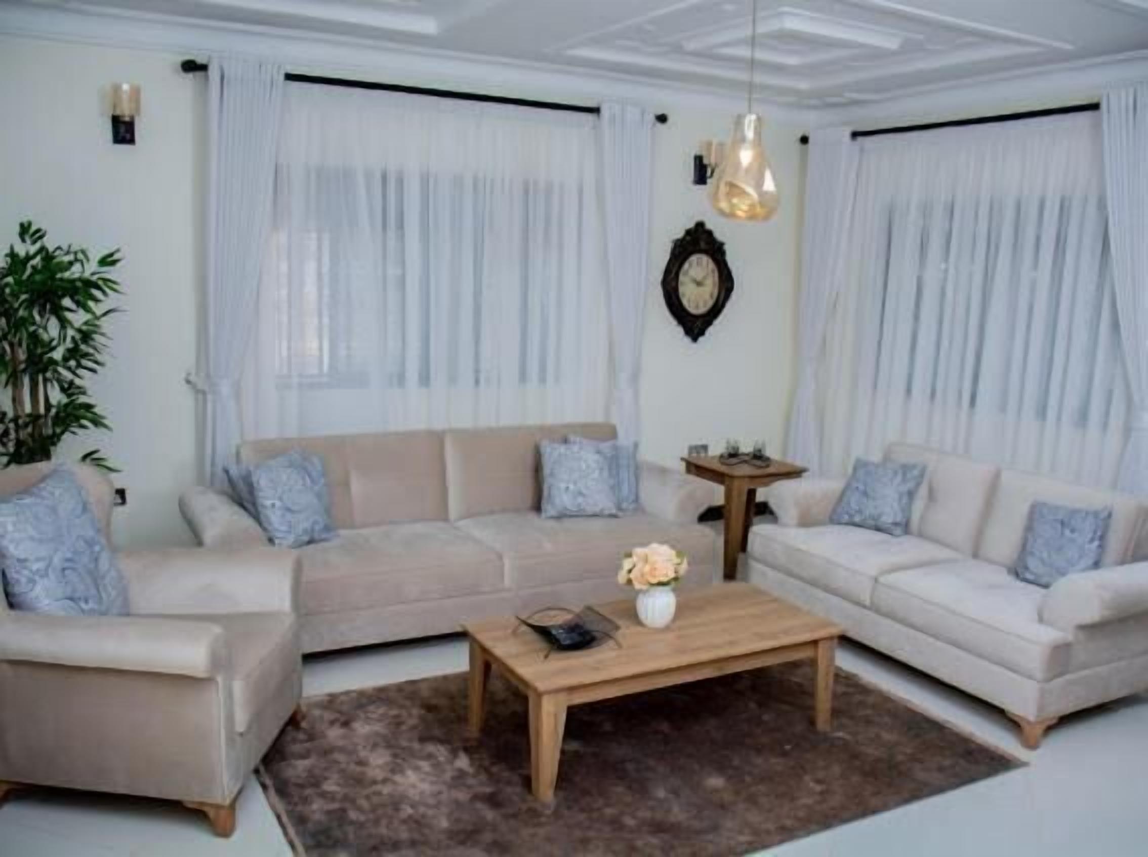 A living room with a beige sofa set, a coffee table, and a potted plant.