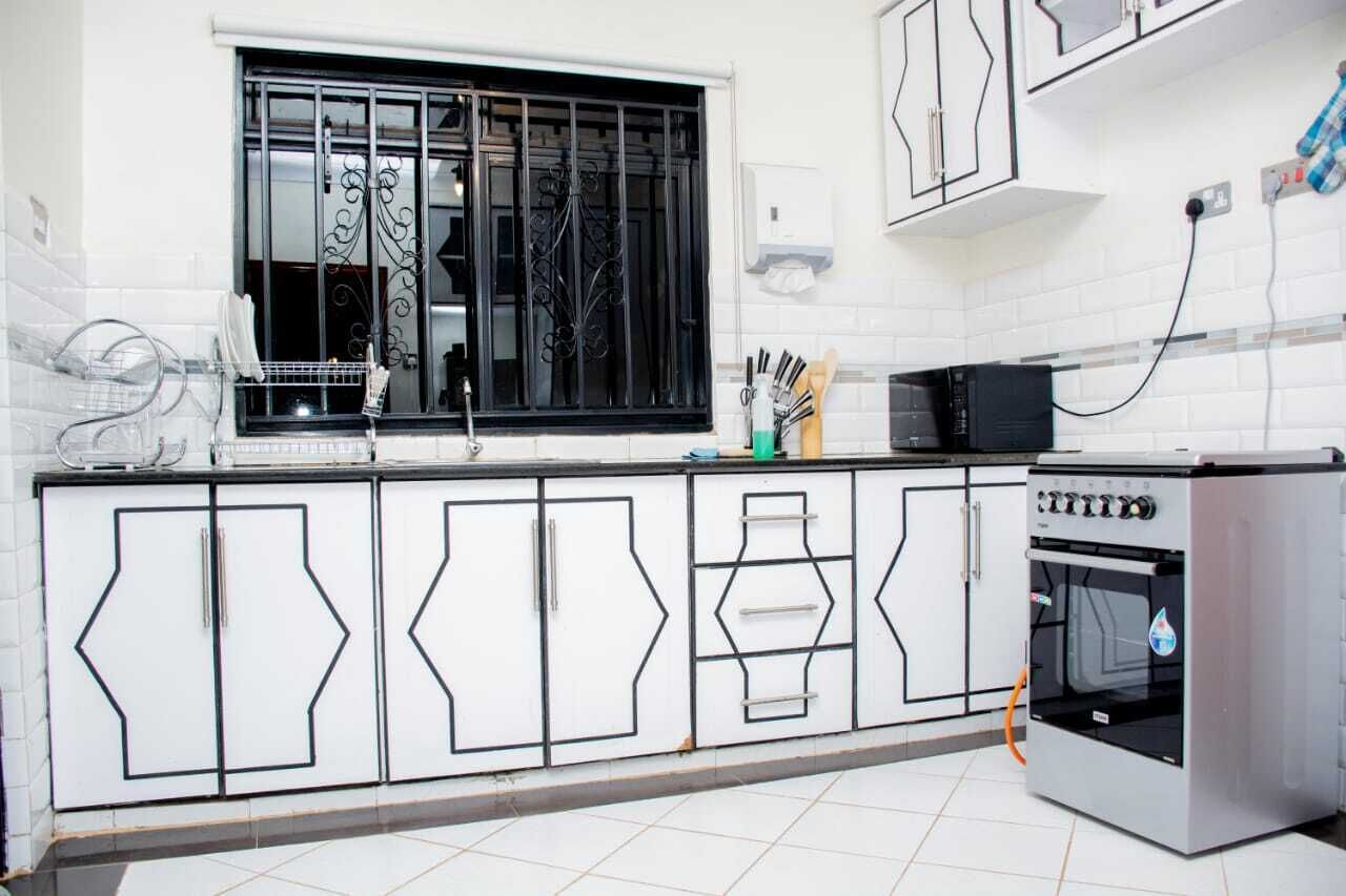 A kitchen with white cabinets, a window with black bars, and a stove.