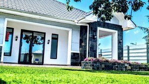 A modern house with a large glass door, a stone facade, and a well-maintained lawn. - BLUEBERRY VILLAS (Eldoret)
