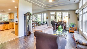 A spacious living room with a large window, a dining area, and a kitchen with wooden cabinets. - Hike, Ski, Fish & Bike: Bellingham All-season Base (Bellingham)