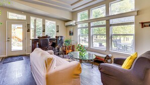 A spacious living room with a sofa, armchairs, a glass coffee table, and large windows offering a view of the outdoors. - Hike, Ski, Fish & Bike: Bellingham All-season Base (Bellingham)