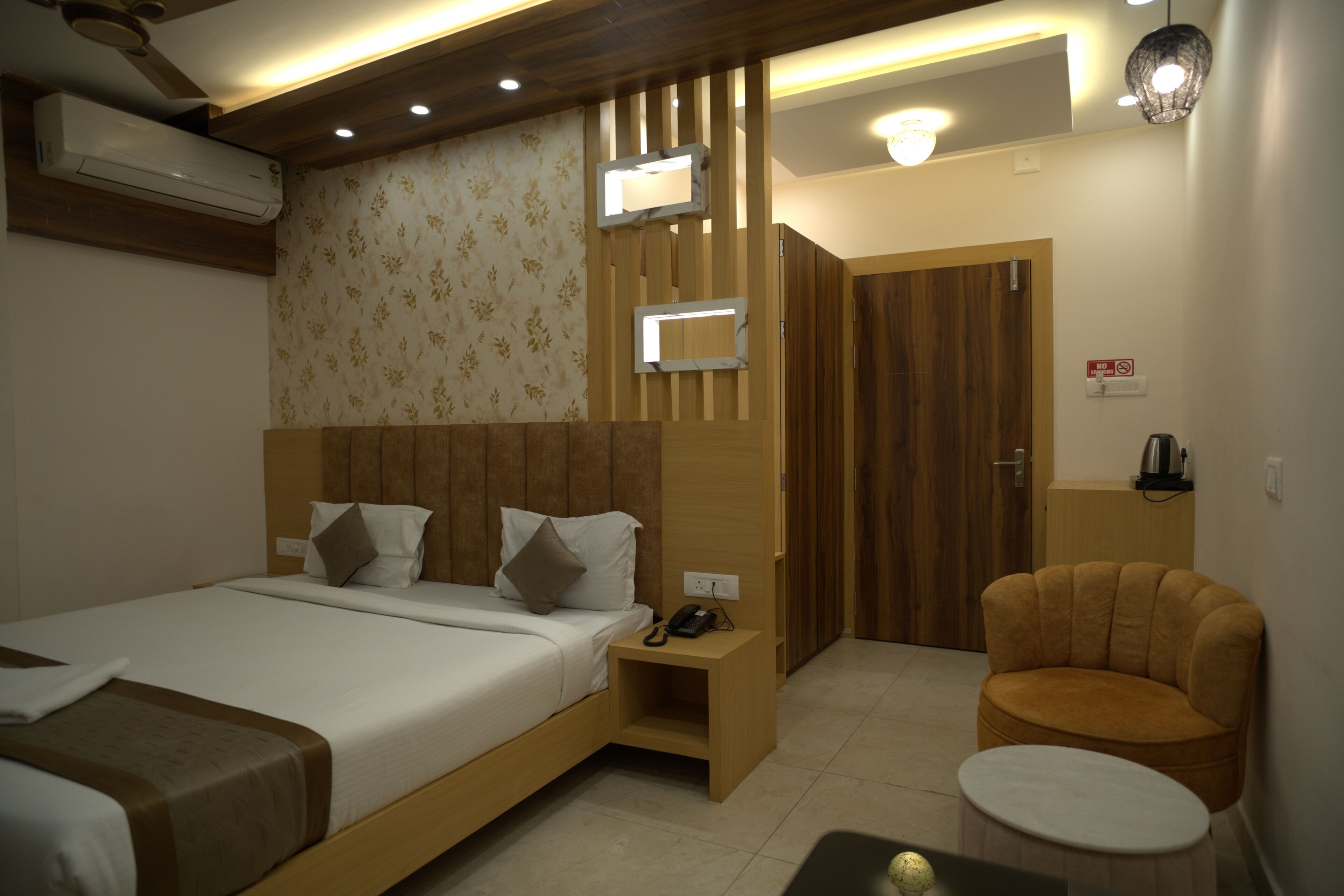 A hotel room with a large bed, a bedside table with a phone, a chair, and a small table.